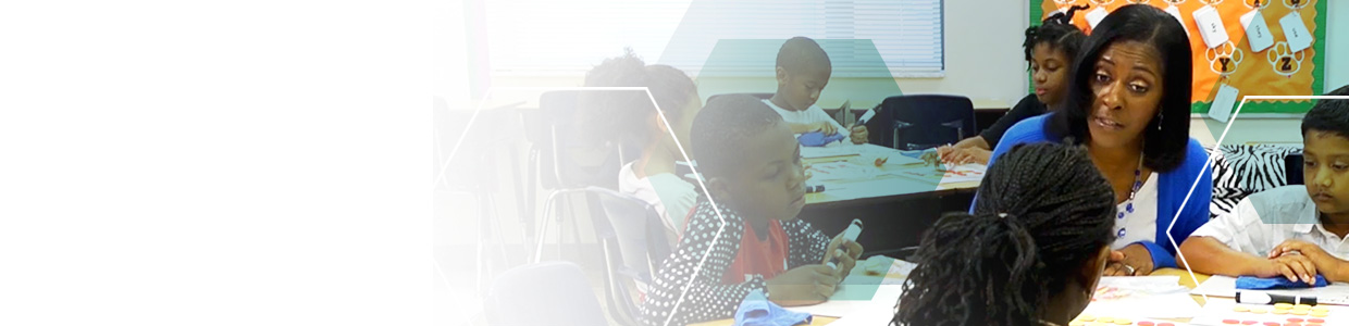 A female teacher working with a group of three elementary school students at a table